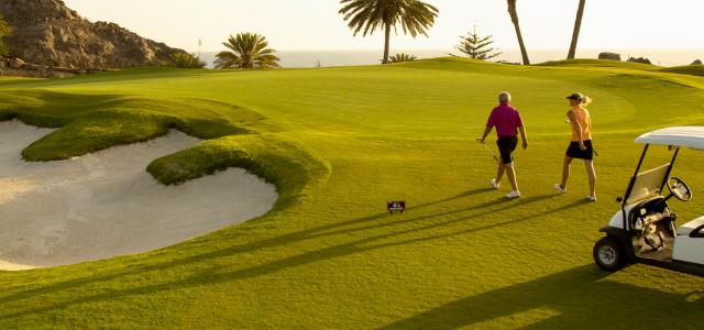 Active senior couple playing golf at sunset